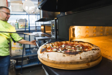 pizza near an electric oven and a chef working in the background. High quality photo - Powered by Adobe