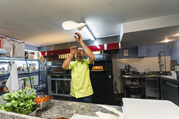 Skilled chef preparing dough for pizza rolling with hands and throwing up. High quality photo