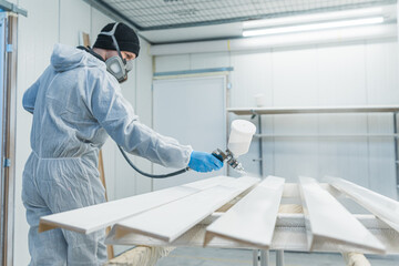 master painter in a factory, industrial painting wood with spray gun. High quality photo