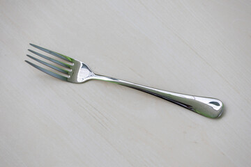 A steel fork silver spoon placed on a wooden background