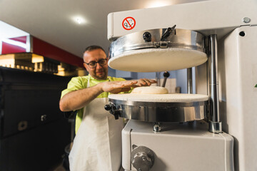 chef putting pizza dough in the pressing apparatus, modern machine. High quality photo