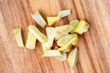 Fresh ginger pieces on a wooden background.