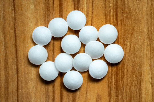 White Naphthalene balls isolated on wooden background. It is also known as moth flakes, naphthalin, antimite, and hexalene. Top view
