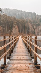 Fototapeta premium Tranquil sunrise mist hovers over wooden bridge on calm lake, surrounded by lush trees
