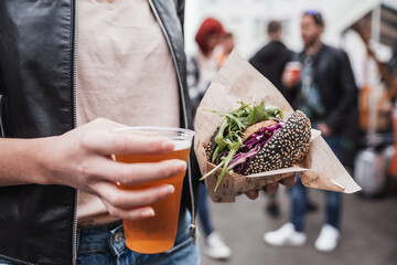 Close up of woman hands holding delicious organic salmon vegetarian burger and homebrewed IPA beer...