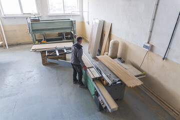 Carpenter cutting a wooden plank with a carpentry machine. High quality photo