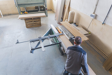 Woodworker cutting wooden plank in the carpentry shop, high-angle view. High quality photo