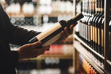 Sommelier Selecting Fine Wine Bottle From Cellar Shelf in Close-Up