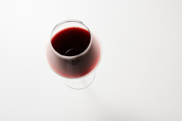 Top view of red drink poured into wine glass on white.
