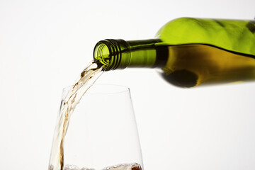 White wine pouring from green bottle, close up.