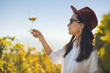 Woman Tasting White Wine in Glass on Plantation of Vineyard - 795245228