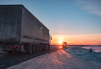 Fototapeta na wymiar Semi truck driving along a snowy highway at sunset in winter