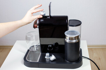close-up of woman making coffee using capsule coffee machine at home