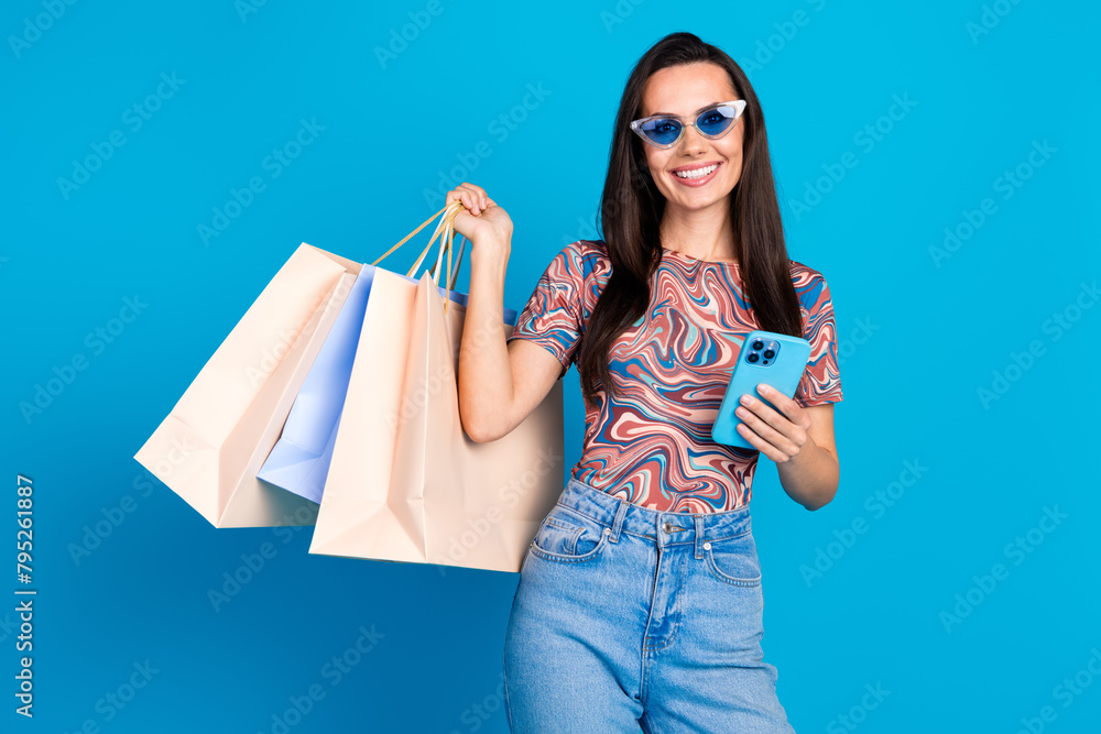 Sticker Photo portrait of pretty young girl sunglass hold device shopper wear trendy colorful clothes isolated on blue color background