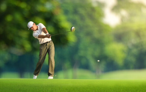 Golfer hitting golf ball with driver.