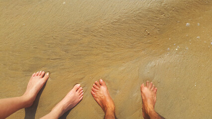 Male and female feet in the sea water with froth