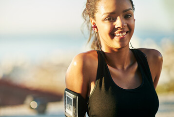 Woman, portrait and outdoor exercise with earphones or arm running strap for podcast, fitness app or workout. Female person, face and smile for music streaming in summer, subscription or playlist