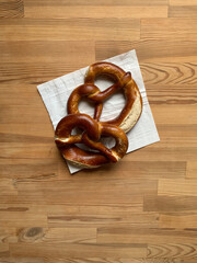 Two pretzel lies on a white paper napkin on a wooden background in the center. View from above.