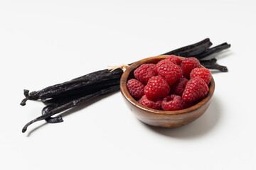 Vanilla beans with raspberries on white background