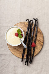 Vanilla pudding with raspberries in white bowl.