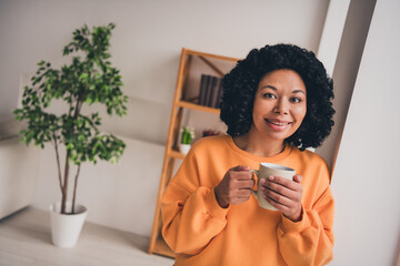 Photo portrait of lovely young lady drink tea coffee dressed casual orange clothes cozy day light home interior living room - obrazy, fototapety, plakaty