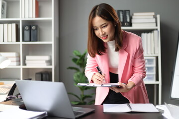 Portrait of attractive Asian businesswoman at desk in office.