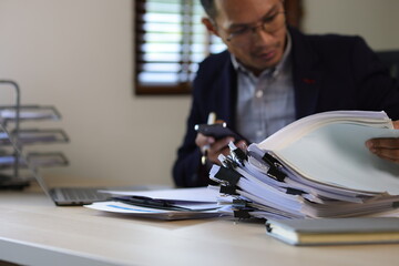 Serious executive businessman is busy with paperwork on the table in the office.