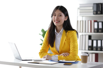 Portrait of attractive Asian businesswoman at desk in office.