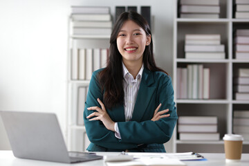 Portrait of attractive Asian businesswoman at desk in office.