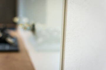 Detail of tempered white glass used as a backsplash in a new modern kitchen with oak countertop, shallow depth of field 