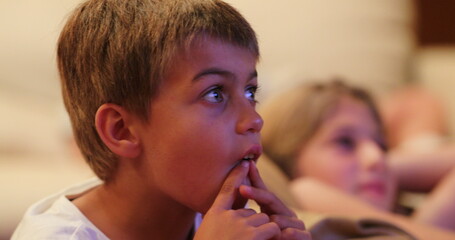 Young boy absorbed by movie watching TV screen