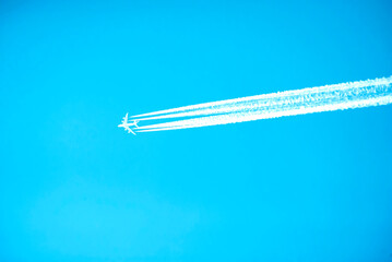 An airplane with four clear lines of contrails against a cloudless sky, the grace of flight. Travel symbol. technological progress, air pollution by chemical sprays from the air