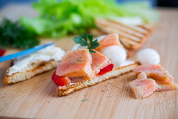 fried toast with salmon, cream cheese, salad, on a wooden table
