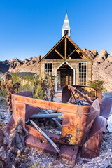 Abandoned church in the Nevada desert at sunset with rusted antique car