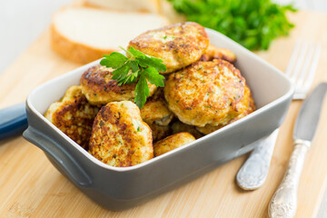 fried meat cutlets in a ceramic form on a wooden table