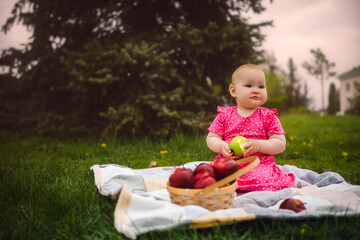 Young Girl in a Pink Dress Enjoying an Apple on a cloudy Day at the Park