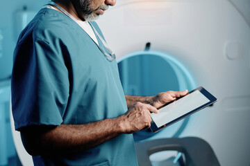 Medium crop shot of biracial doctor using digital tablet at work in MRI room, copy space