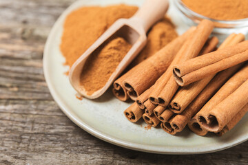 Cinnamon sticks on a textured wooden background. Cinnamon roll. Spicy spice for baking, desserts and drinks. Fragrant ground cinnamon. cinnamon powder Close-up. Place for text. copy space