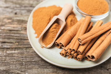 Cinnamon sticks on a textured wooden background. Cinnamon roll. Spicy spice for baking, desserts and drinks. Fragrant ground cinnamon. cinnamon powder Close-up. Place for text. copy space
