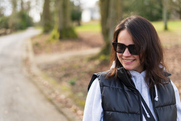 Portrait of a beautiful young woman in black sunglasses standing in a park