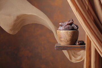 Medjool dates in wooden dish on a brown background.