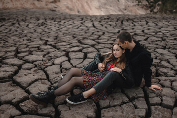 beautiful and young lovers, a guy and a girl are walking on an unusual terrain similar to the moon. Happy couple of European appearance on a first date in nature, smiling and relaxing