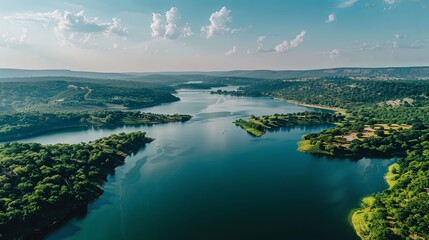 A drone aerial view of a large and expansive lake surrounded by lush greenery and rolling hills, showcasing the beauty and grandeur of nature's inland waterways.