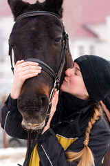 Intimate moment between person and horse in the snow.