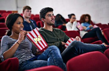 Movie, date and couple in cinema at night with popcorn to relax and watch in theatre with happiness. Film, experience and people in audience enjoy funny comedy, drama performance or eating snack food