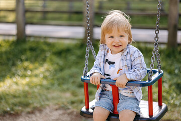 a small child with blond hair sits on a swing
