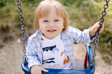 a small child with blond hair sits on a swing