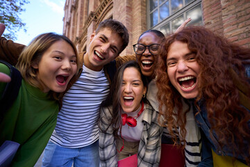 Portrait of multiracial group student people hugging looking excited at camera together enjoying at university campus. Diverse cheerful young friends in community with big smiles having fun outdoor