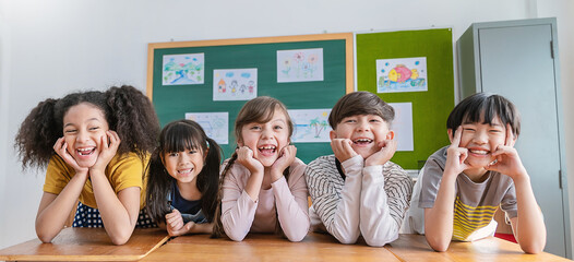Portrait of five children having good time in classroom, asian caucasian children together in...