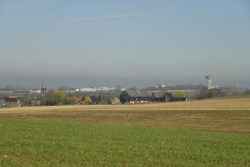 Fototapeta premium Au loin en contrebas ,le village de Ghislenghien sous une chape de pollution en hiver à Ath 
